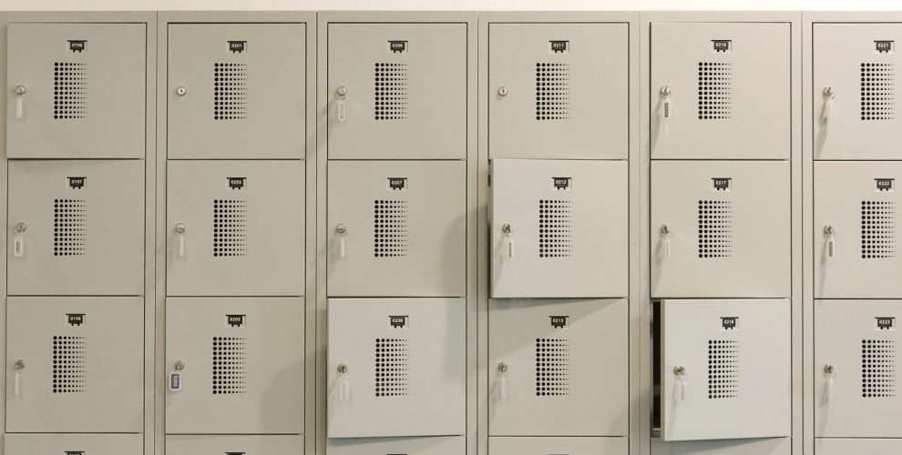 A row of grey metal lockers indoors with some doors ajar.